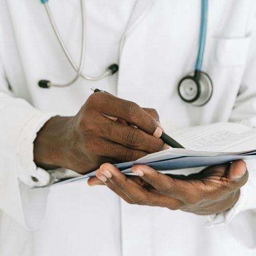 pexels-photo-4989141-4989141 Professional doctor writing on a clipboard with a stethoscope in a medical office.